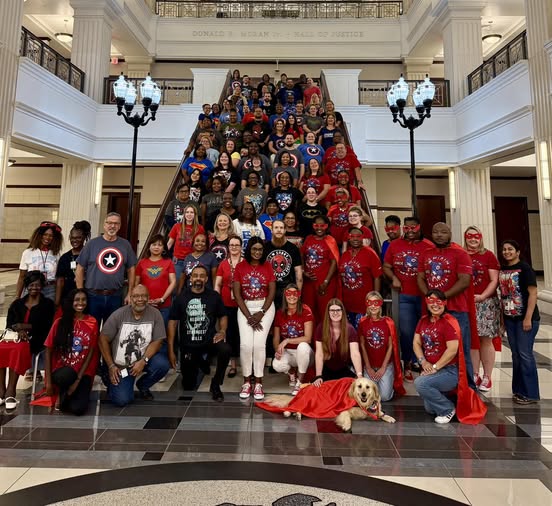 Clerk employees posed on a staircase wearing superhero shirts
