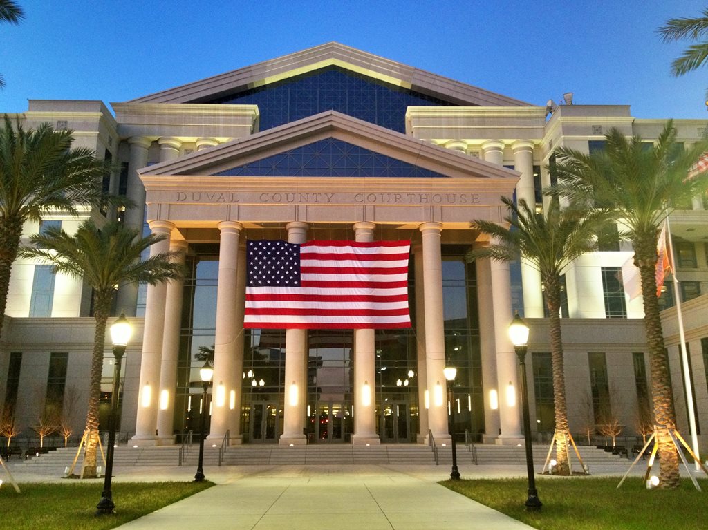 picture of the Duval County Courthouse with a large American flag drapped across the front