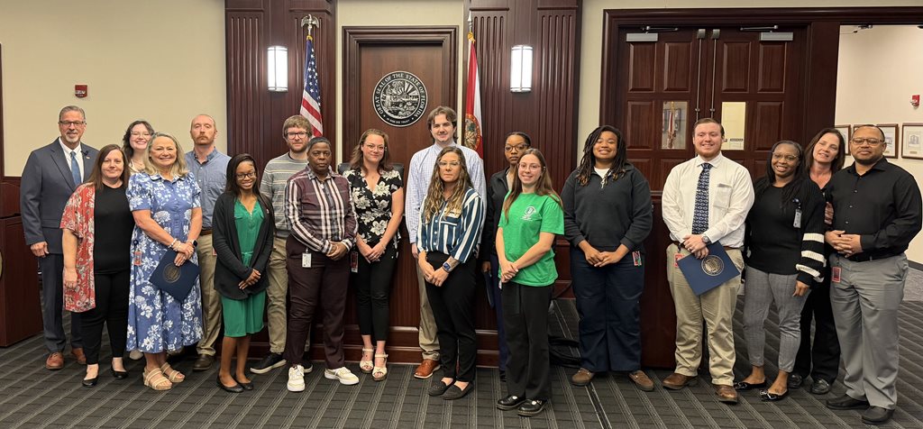 photo of Clerk employees posing with Clerk Phillips in front of a judge's bench
